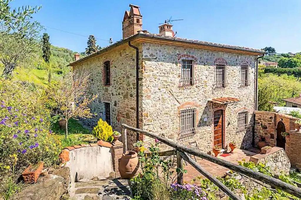 an old stone house with a staircase in front of it at Villa Pera by Nicola Real Estate in Corsanico-Bargecchia