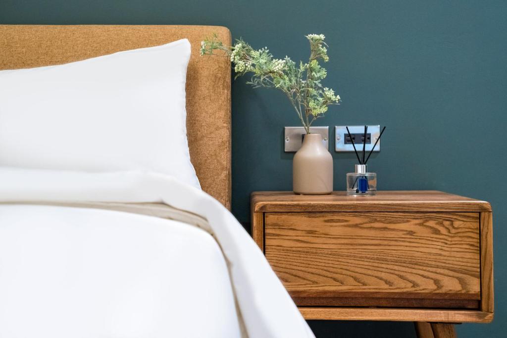 a bed with a side table with a vase on it at Lin Suites by Olala Homes in Taipei