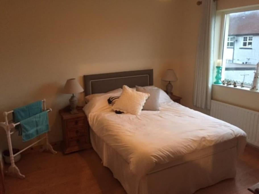 1 dormitorio con 1 cama con sábanas blancas y ventana en Primrose Cottage, Bushmills - Cosy Self Catering Property, en Bushmills