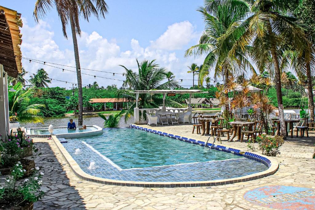 una piscina con mesa, sillas y palmeras en Pousada Paradiso Tropical, en Praia do Frances