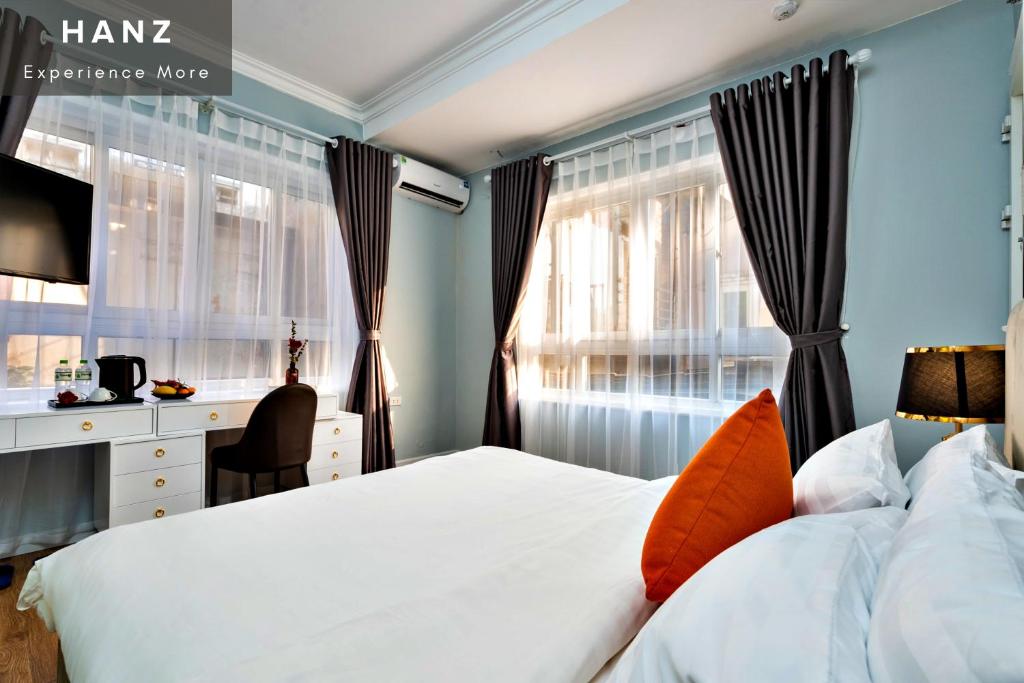 a bedroom with a bed and a desk and windows at Memory Legends Hotel in Hanoi