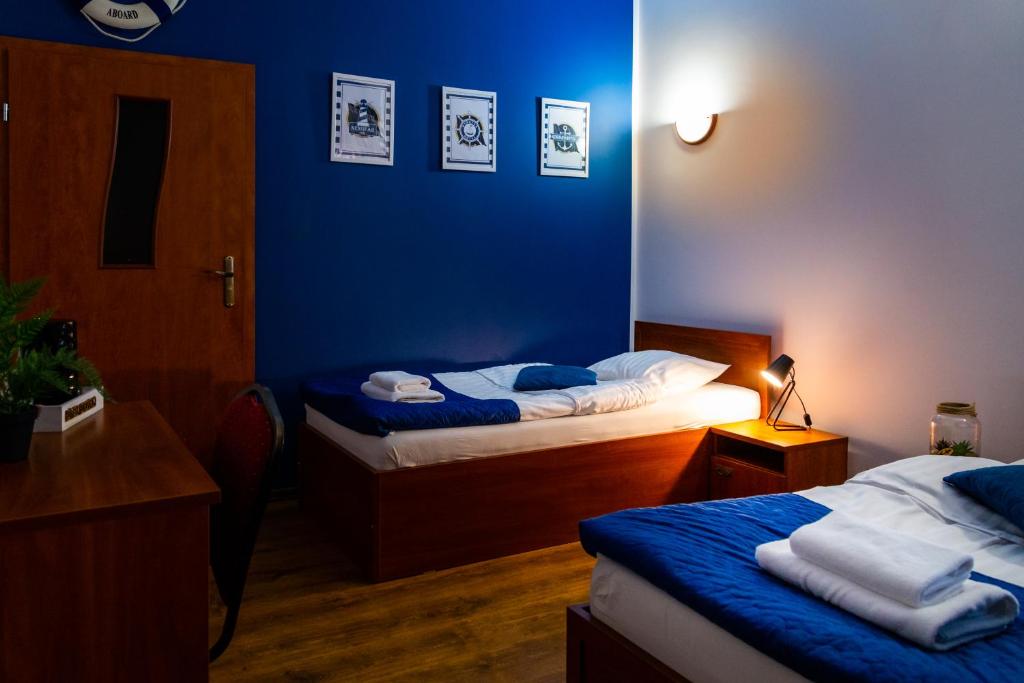 Cette chambre comprend 2 lits et un mur bleu. dans l'établissement Hotel Nenufar, à Kościan