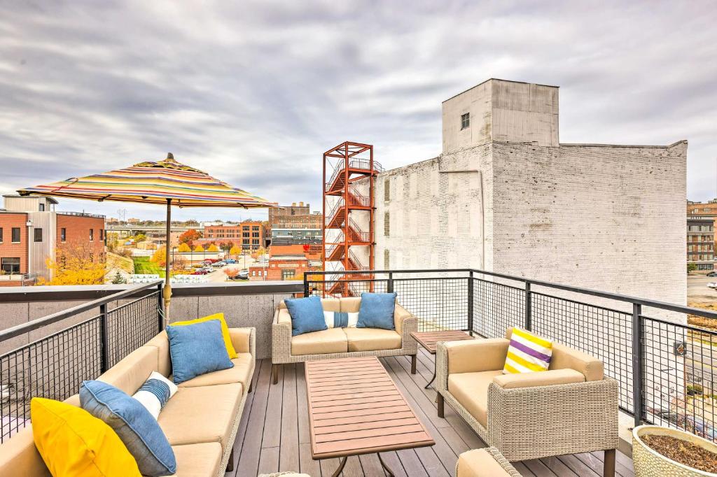 a balcony with couches and an umbrella on a building at Downtown Condo with Rooftop Patio and City Views! in Omaha