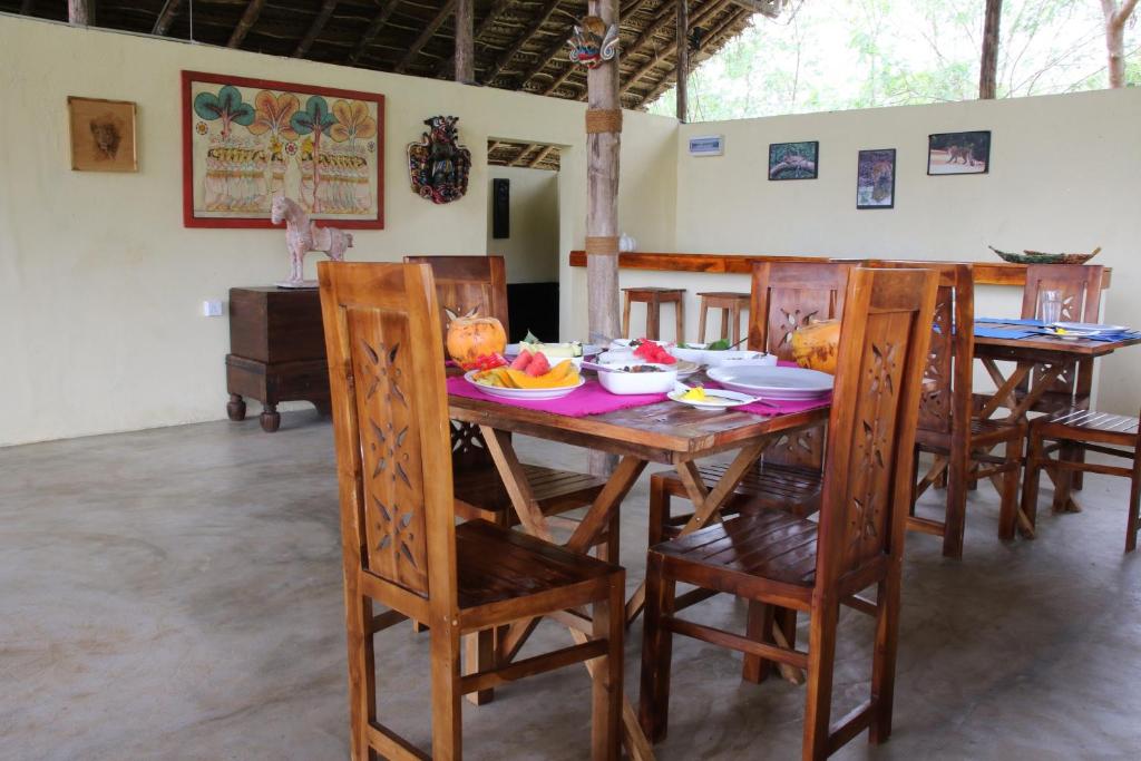 a dining room with a wooden table and chairs at Nirvaan Safari Lodge in Wilpattu