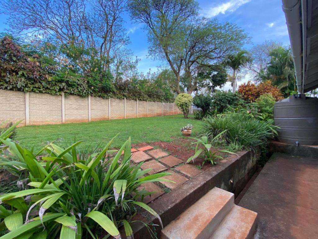 a garden with a fence and some plants at Dickens Garden Flat in Empangeni