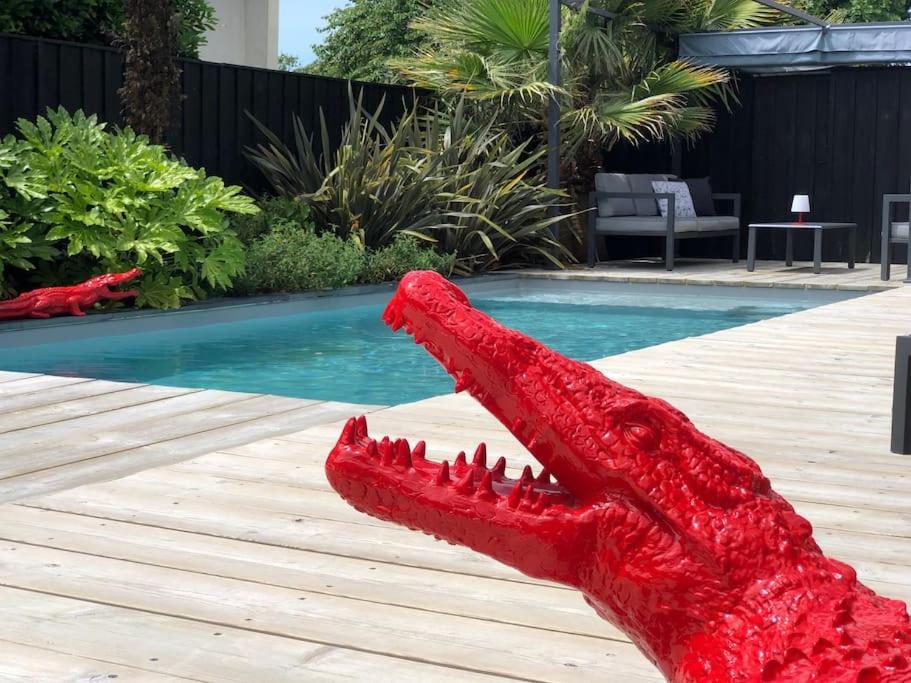 a red crocodile statue sitting next to a pool at Nanie - Villa centre-ville, piscine, wifi - La Teste de Buch in La Teste-de-Buch