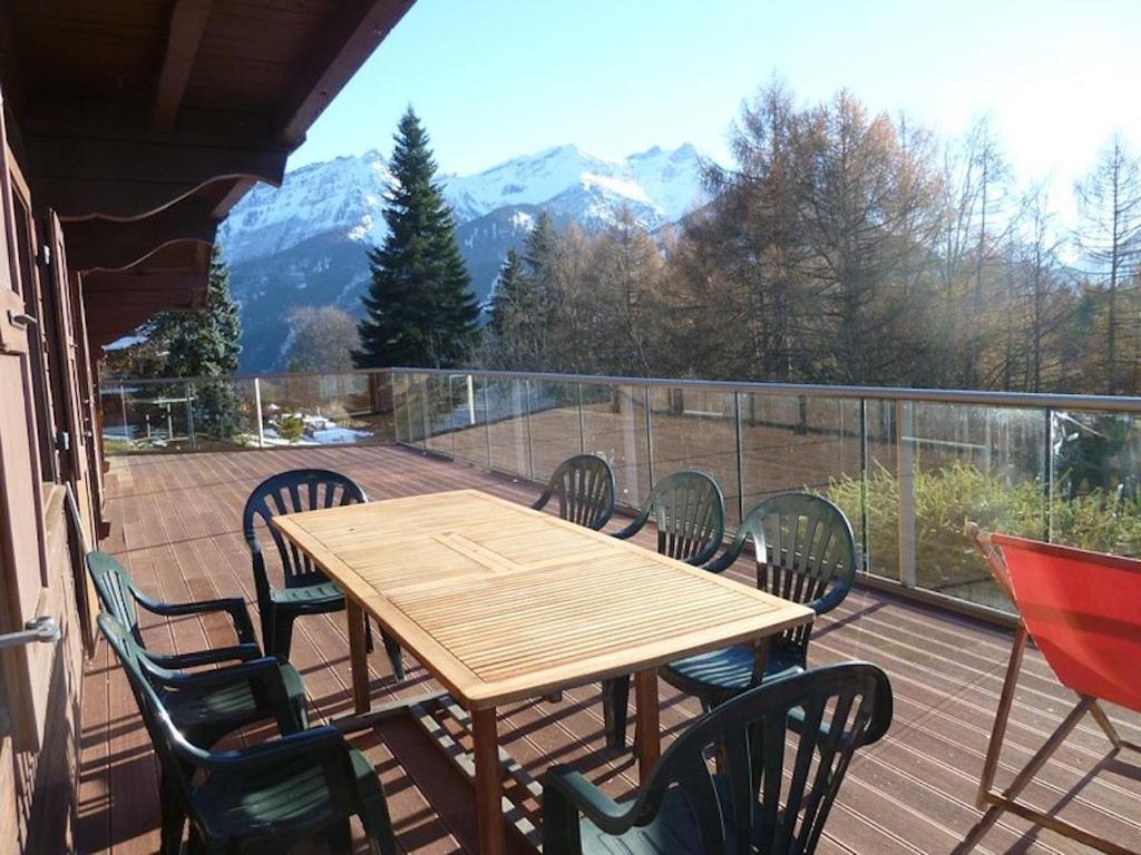 a wooden table and chairs on a balcony with mountains at Chalet traditionnel avec jacuzzi extérieur in Bex