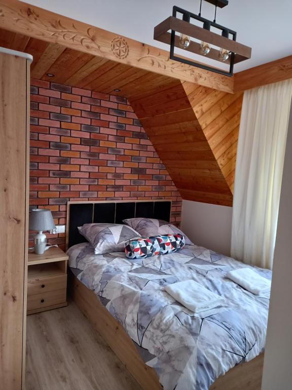 uma cama num quarto com uma parede de tijolos em Apartament 6 osobowy Pasternik em Małe Ciche