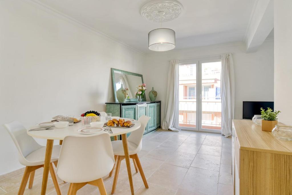 une cuisine et une salle à manger avec une table et des chaises blanches dans l'établissement Appartement Bricka - Welkeys, à Antibes