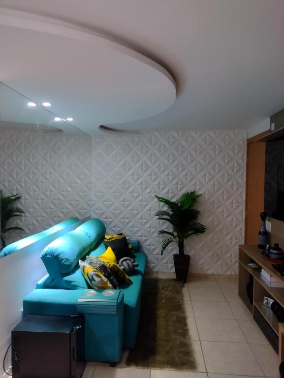 uma sala de estar com um sofá azul num quarto com uma planta em Apartamento mobiliado e aconchegante no Rio de Janeiro