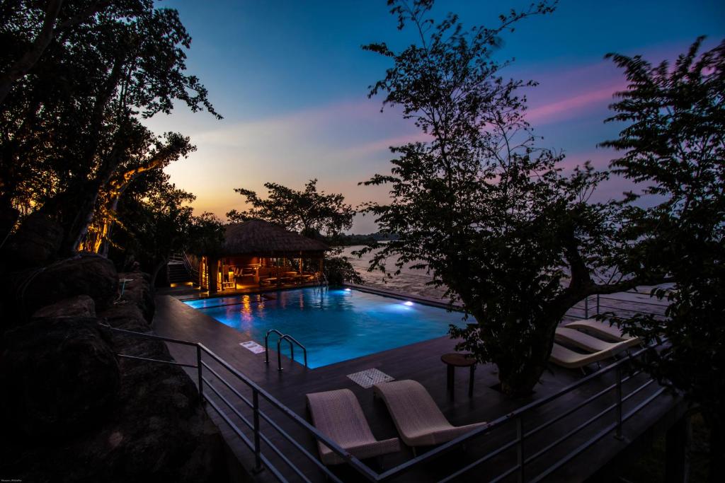 a swimming pool with lounge chairs and the sunset at Oruwa Boutique Villas in Arugam Bay