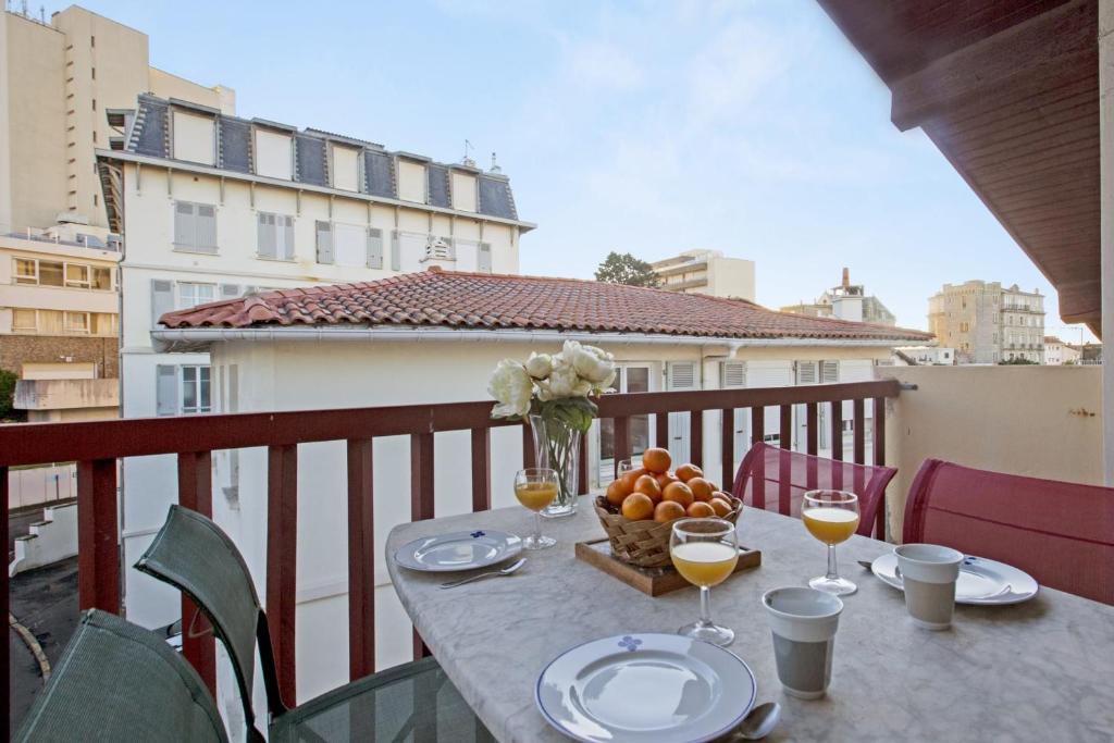 a table with glasses of wine and a bowl of fruit on a balcony at Large studio with balcony at the heart of Biarritz - Welkeys in Biarritz