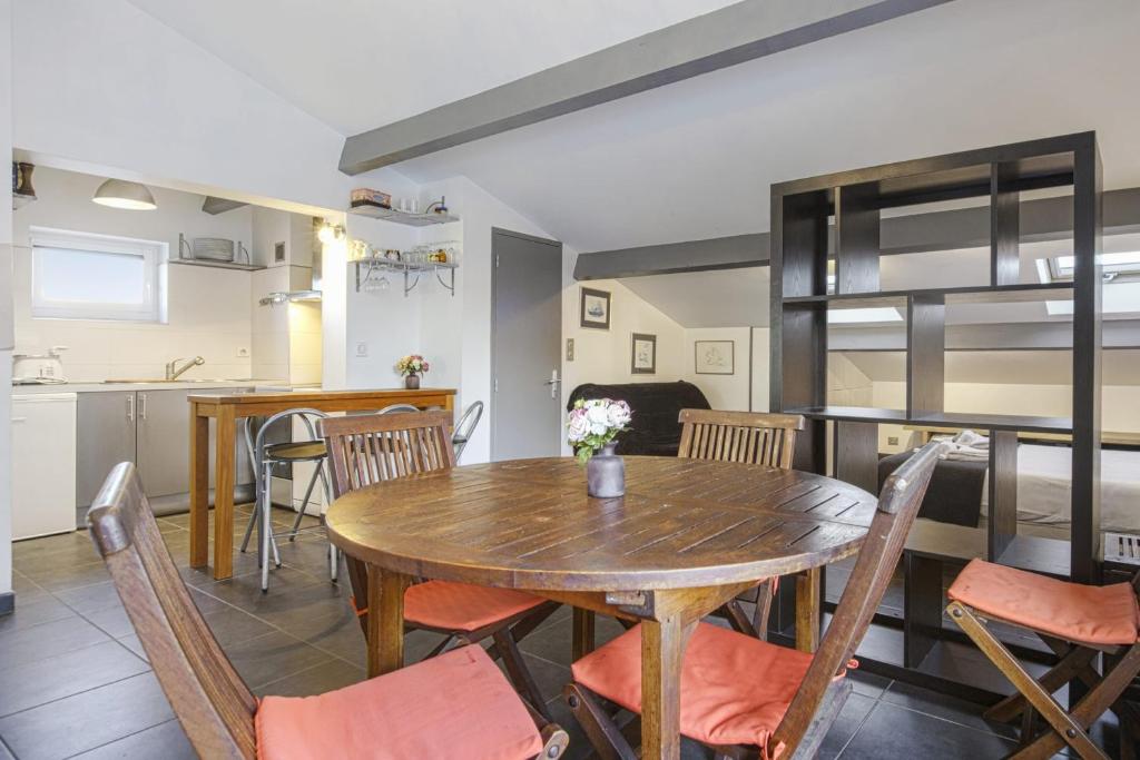 a kitchen and dining room with a wooden table and chairs at Large studio with balcony at the heart of Biarritz - Welkeys in Biarritz