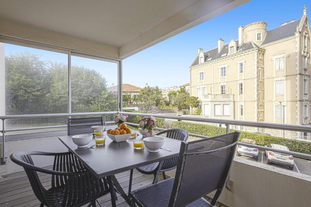 einen Tisch und Stühle auf einem Balkon mit Blick auf ein Gebäude in der Unterkunft Nice flat with terrace and parking - Biarritz - Welkeys in Biarritz