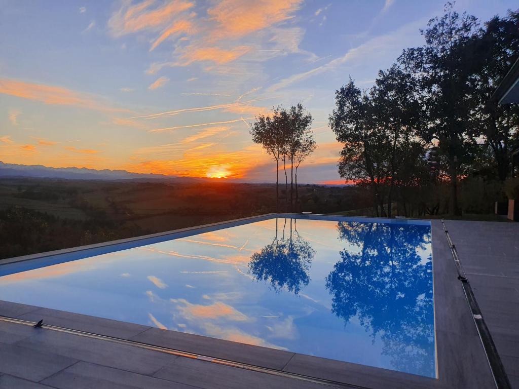 een zwembad met een zonsondergang op de achtergrond bij Villa le Moulin in Unzent