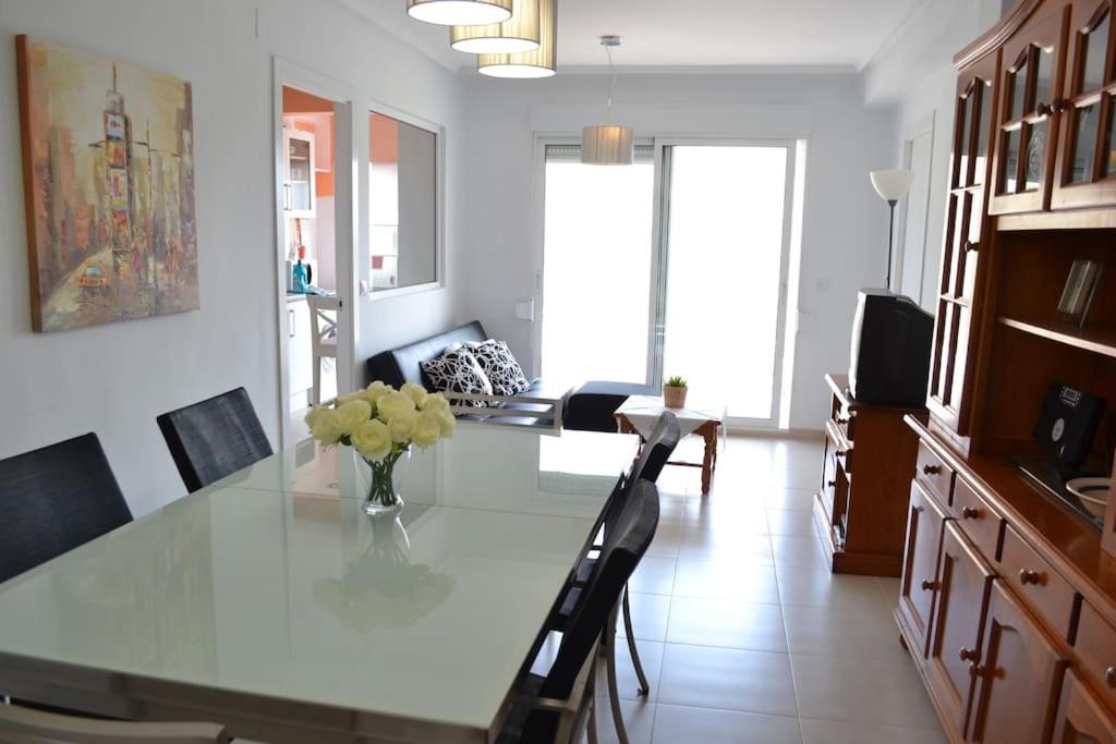 uma sala de jantar com uma mesa de vidro e cadeiras em Apartamento junto a playa y cerca de campo de golf em El Perellonet