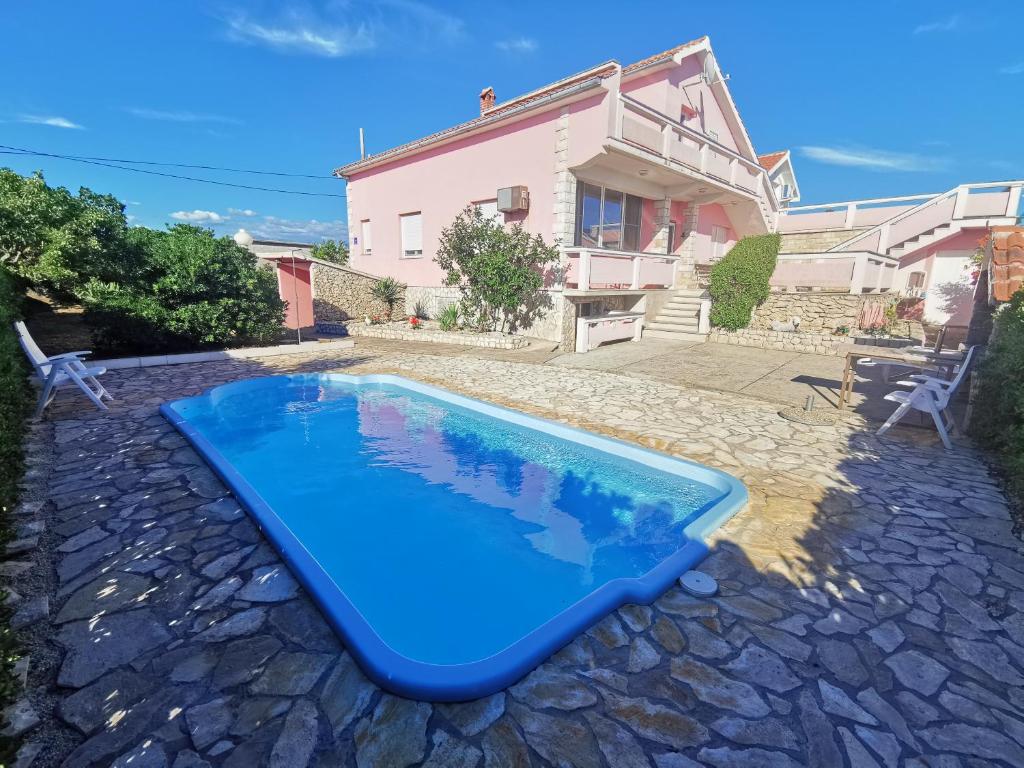 a blue swimming pool in front of a house at Guest house with pool Ante in Vrsi