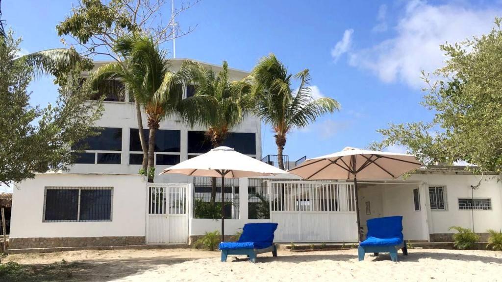 two blue chairs and umbrellas in front of a building at Casa Maya Playa El Yaque in El Yaque