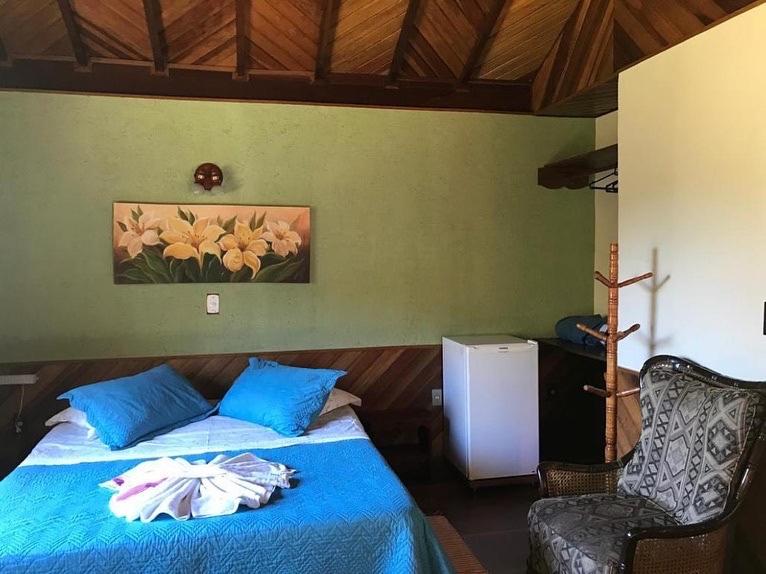 um quarto com uma cama com lençóis azuis e uma cadeira em Chalés Aguá Cristalina em Visconde de Mauá