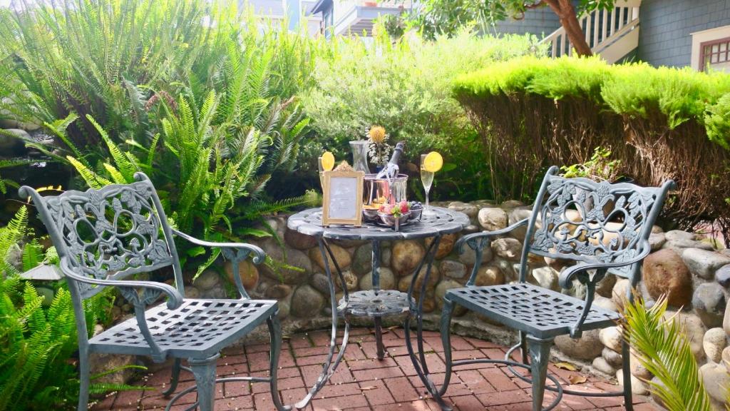 a patio table and chairs in a garden at The Old St Angela Inn in Pacific Grove