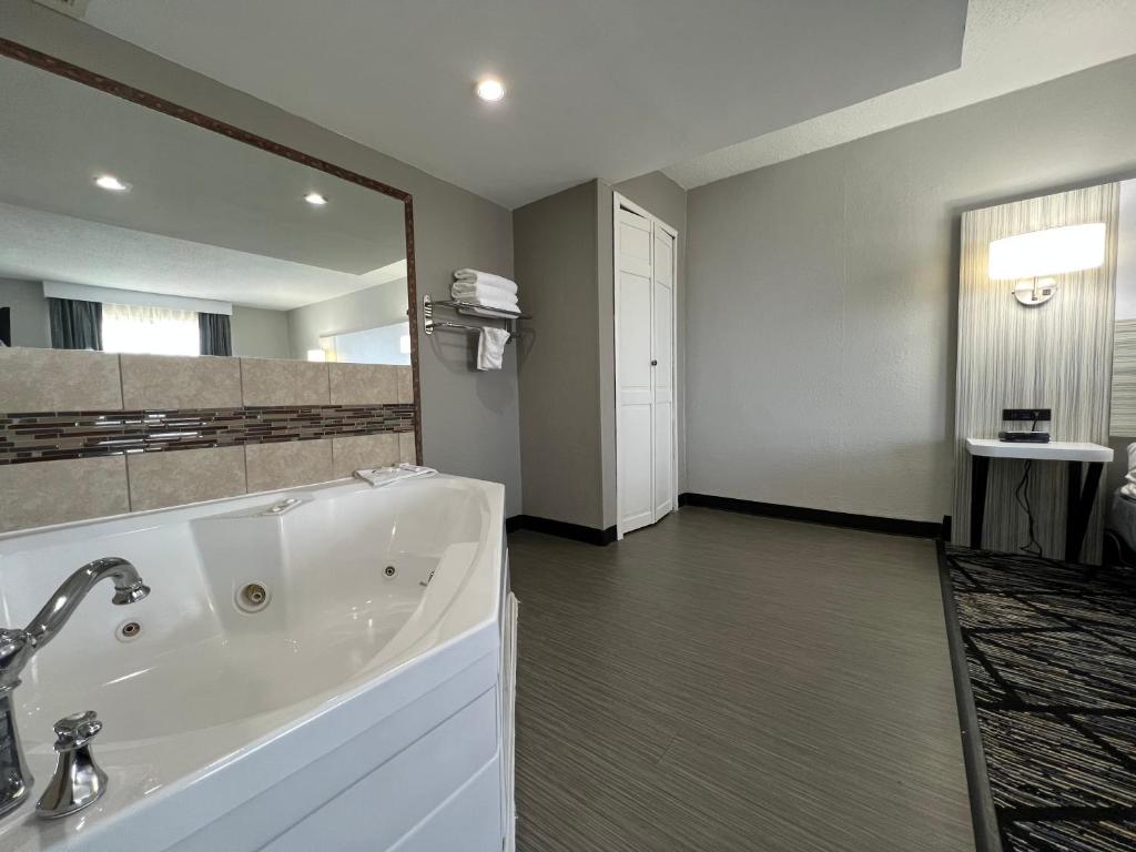 a large bathroom with a tub and a large mirror at Baymont by Wyndham Peoria in Peoria