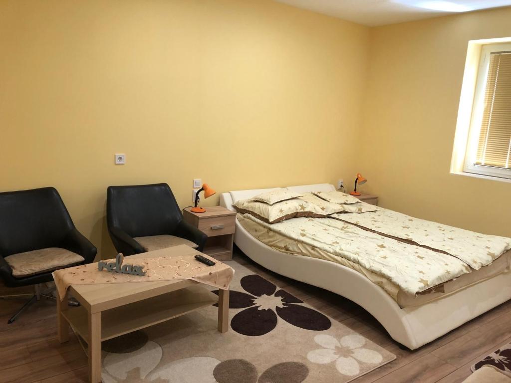 a bedroom with a bed and two chairs and a table at Relax Bogács in Bogács