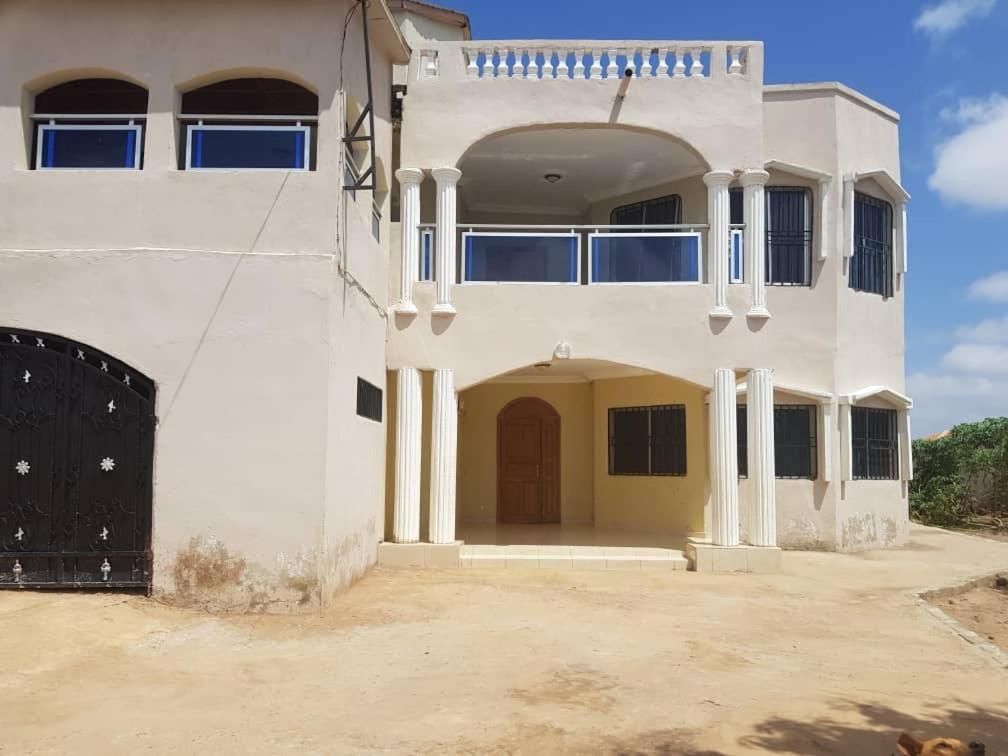 a large white house with a large entry way at Touray Guest House in Old Yundum
