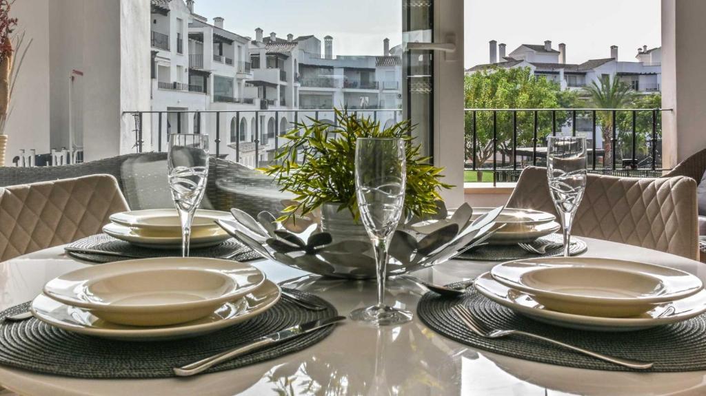 a dining table with plates and glasses on a balcony at First Floor Apartment on La Torre Golf Resort- BO1212LT in Torre-Pacheco