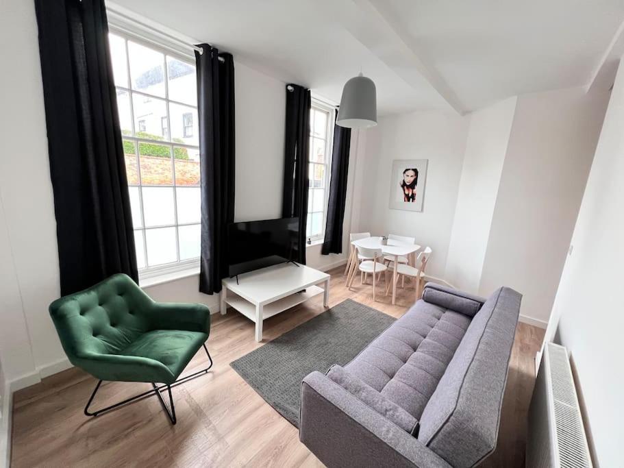 a living room with a couch and a green chair at Spacious modern apartment. Centre of Southwell. in Southwell