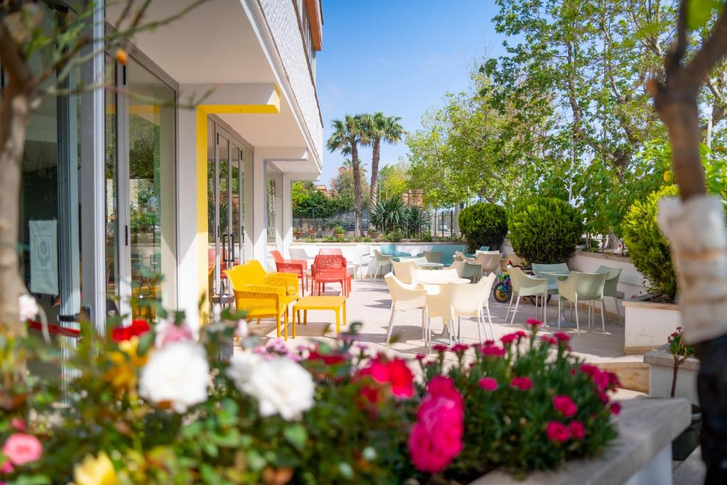 patio z krzesłami, stołami i kwiatami w obiekcie Hotel Royal w mieście Giulianova