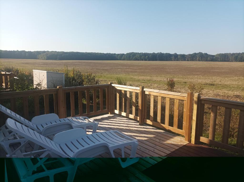 zwei Gartenstühle auf einer Terrasse mit Blick auf ein Feld in der Unterkunft Mobil home Le Galland de Dugny in Onzain