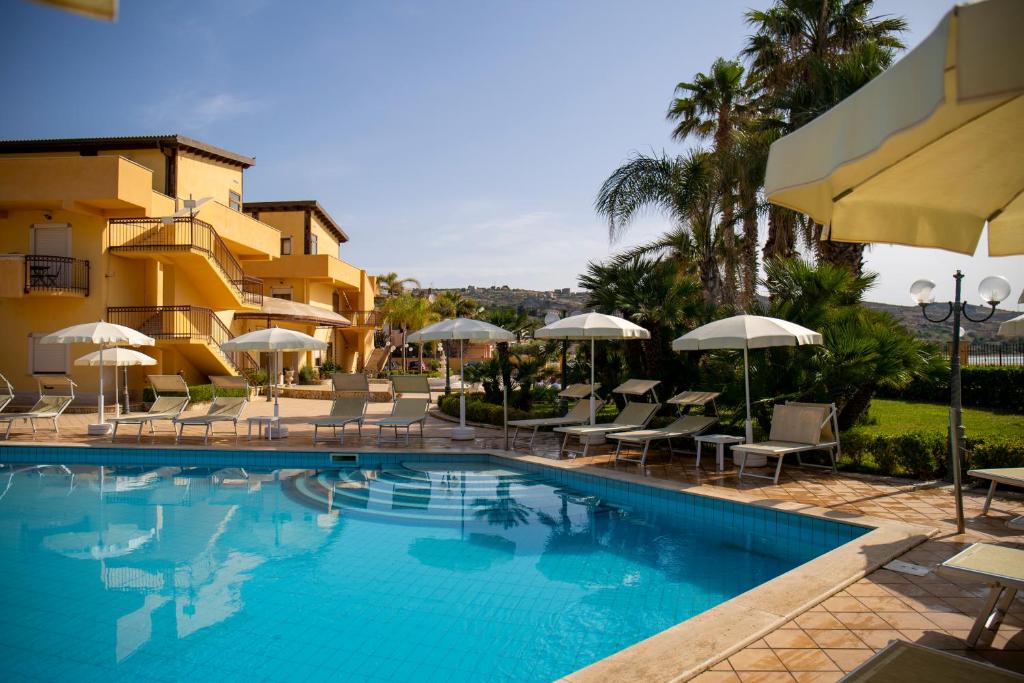een zwembad in een hotel met stoelen en parasols bij Hotel Villa Romana in Porto Empedocle
