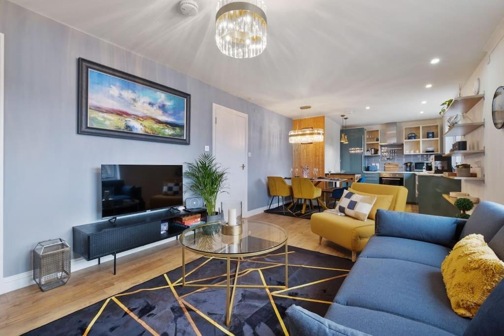 a living room with a blue couch and a table at Boutique Beachside Apartment with Jacuzzi Bath, Findhorn in Findhorn