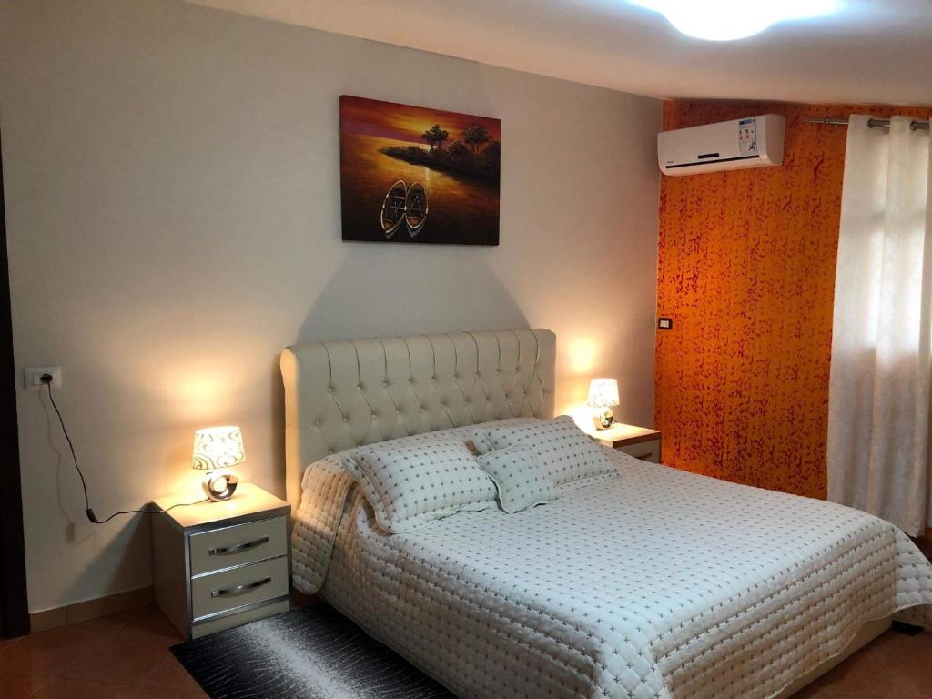 a bedroom with a bed and two night stands with lamps at Villa Ceni in Elbasan