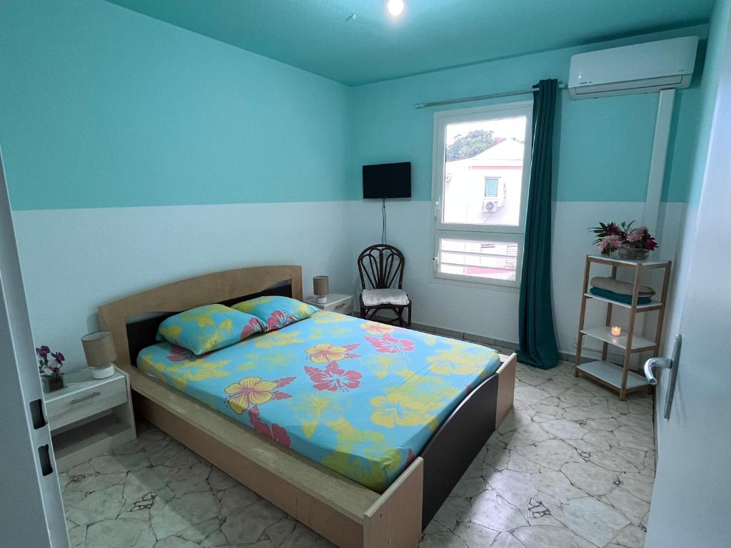 - une chambre avec un lit aux murs bleus et une fenêtre dans l'établissement Chambre d'hôte à 5Mn de l’aéroport, à Les Abymes