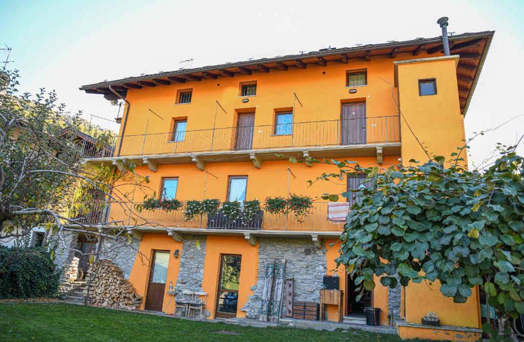 een oranje gebouw met een balkon erboven bij Stars Apartments Gressan in Cerise
