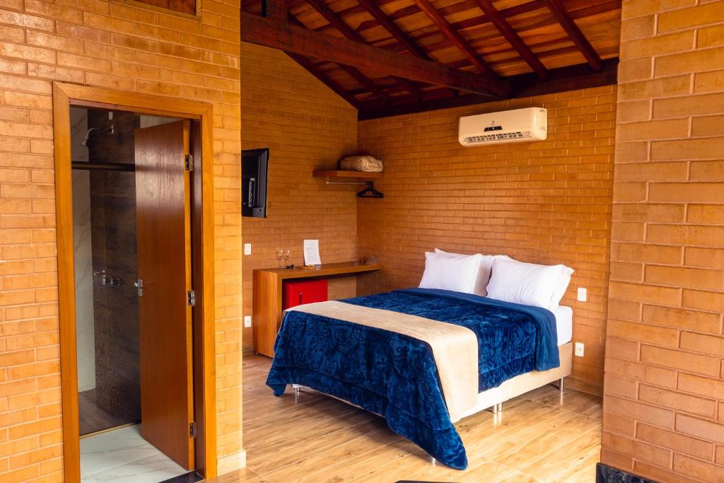 a bedroom with a bed in a brick wall at Chalés Estância Campestre in Capitólio