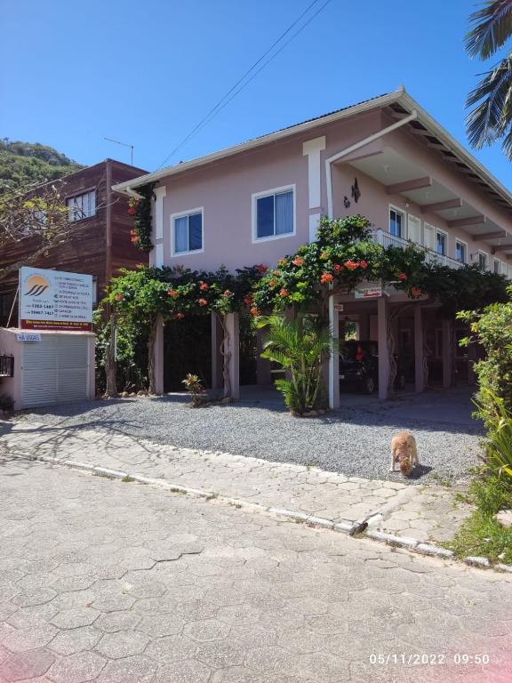 a dog sitting in front of a house at Pousada Águas do Embaú in Guarda do Embaú