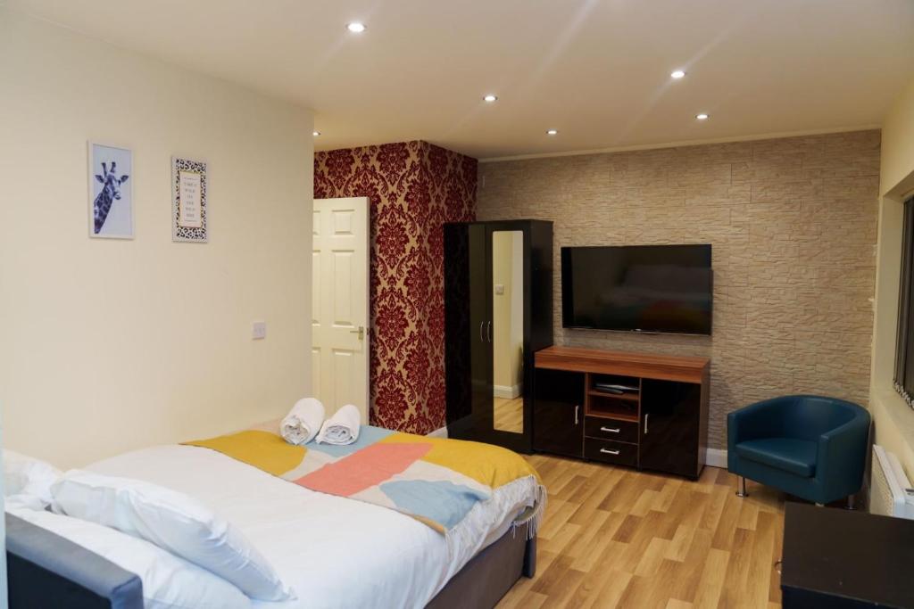 a bedroom with a bed and a flat screen tv at Roundhay Apartments in Leeds