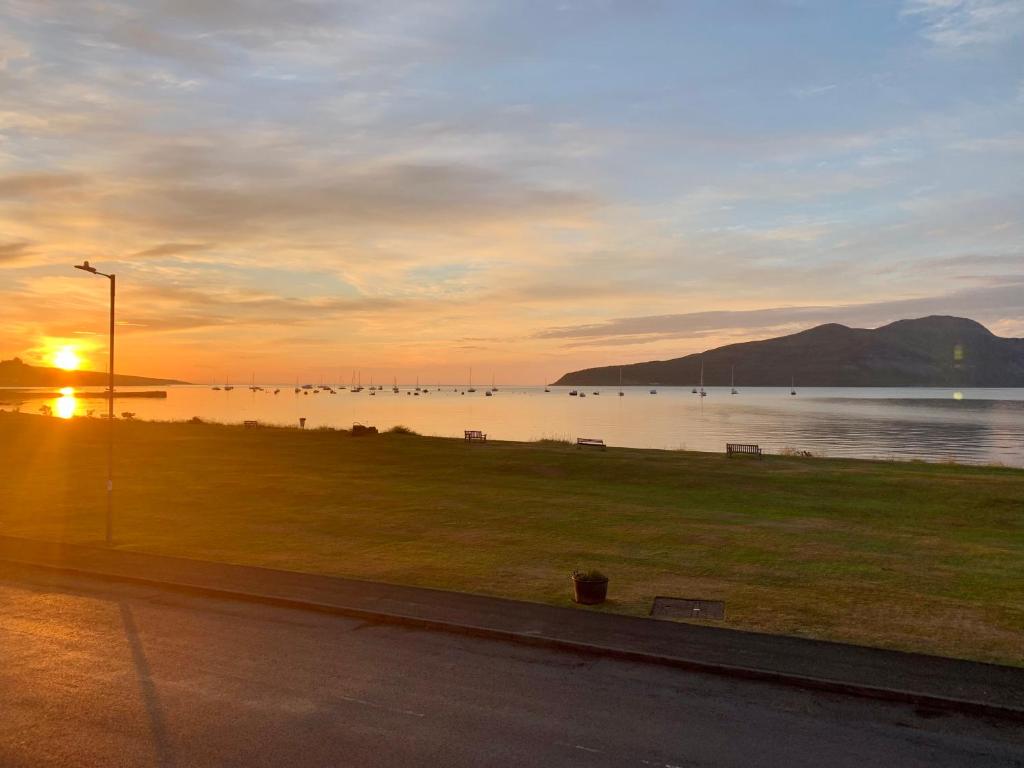 un coucher de soleil sur une étendue d'eau avec un parc dans l'établissement This must be the place - Arran, Lamlash, à Lamlash