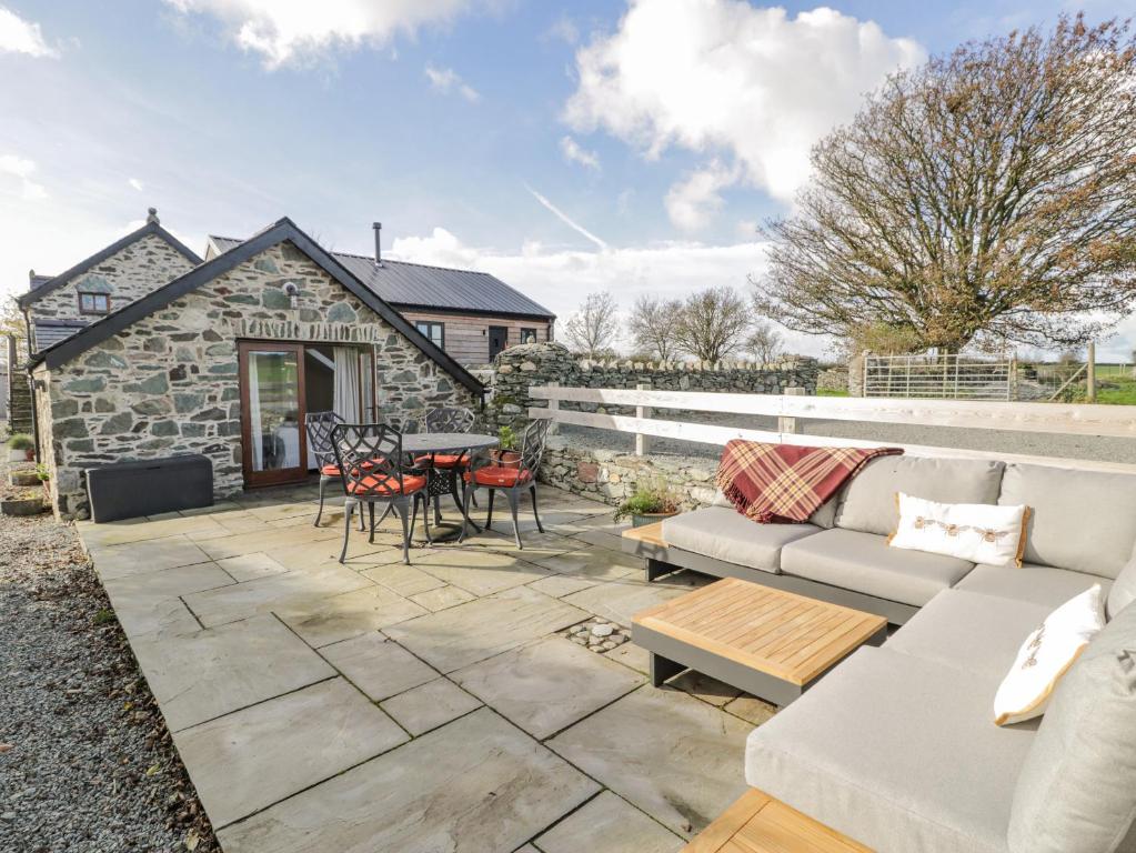 a patio with a couch and a table and chairs at Cwch Gwenyn in Holyhead