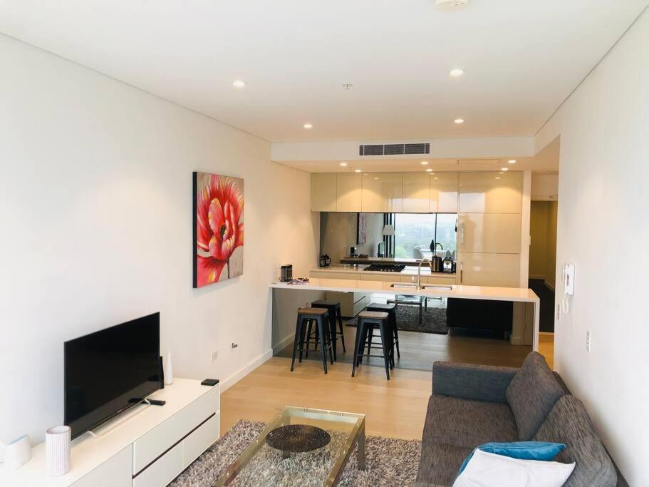 a living room with a couch and a kitchen at Great Corporate One Bedroom ATC006911 in Sydney