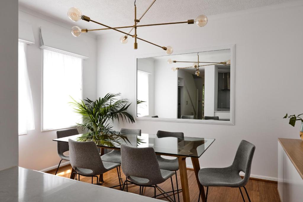 a dining room with a table and chairs and a mirror at Stylish Townhouse in Melbourne's Playground in Melbourne