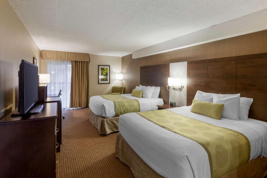 a hotel room with two beds and a flat screen tv at Best Western Plus Leamington Hotel & Conference Centre in Leamington