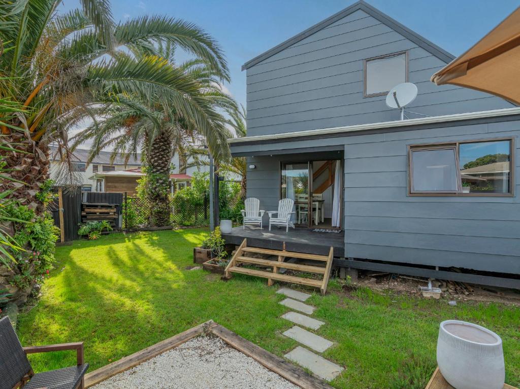 a backyard with a blue house with a patio at Surfscape - Whitianga Holiday Home in Whitianga