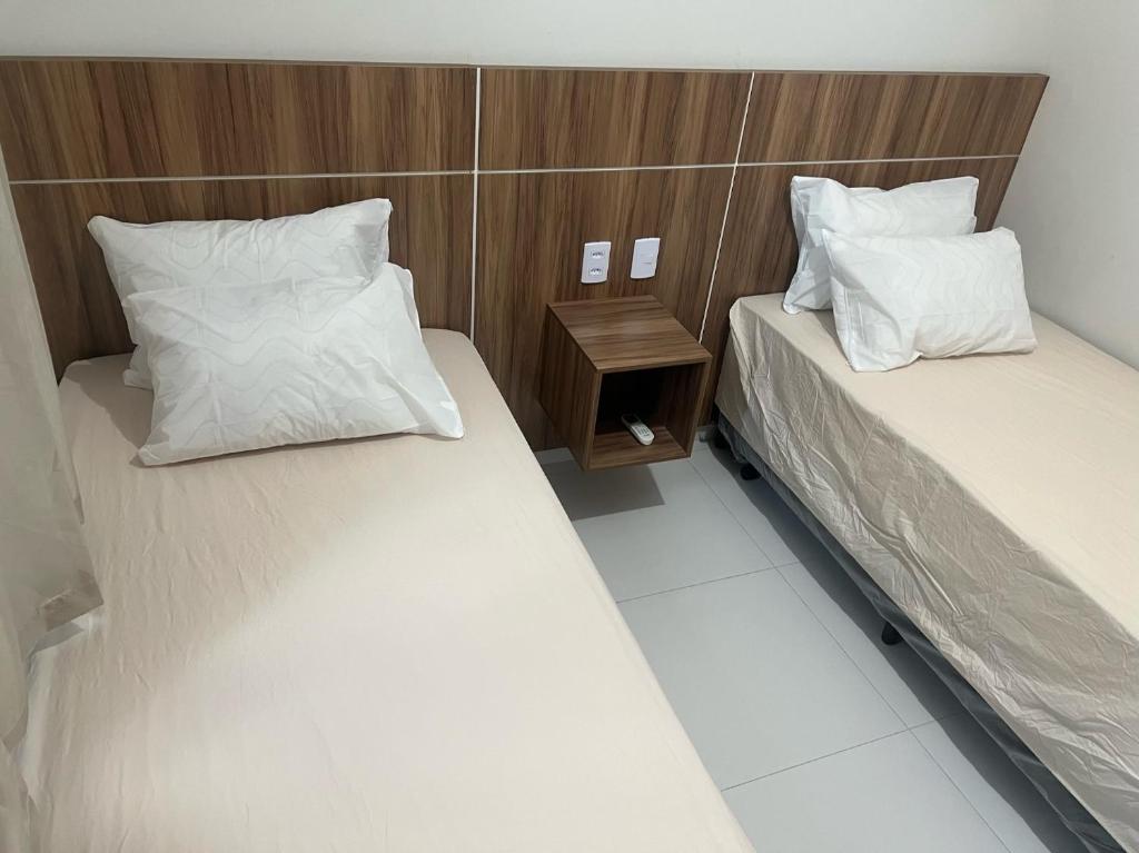 a room with two beds and a night stand at Apartamento nos Lencois Confort in Barreirinhas