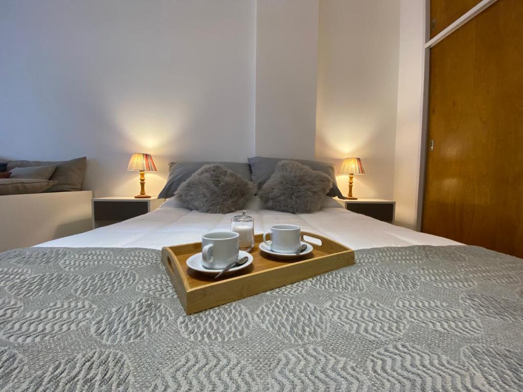 - un plateau avec 2 tasses sur un lit et 2 lampes dans l'établissement Monoambiente de diseño confortable -Puerto Madryn, à Puerto Madryn