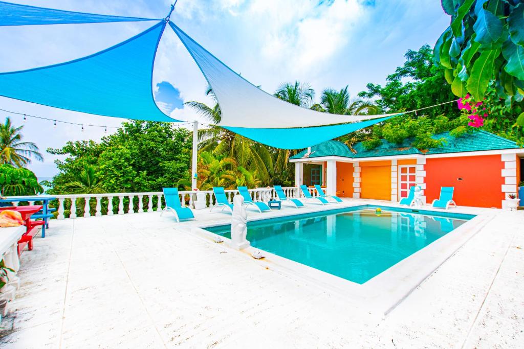 uma piscina com cadeiras e um guarda-sol azul em Palms Cottage at Viking Hill em Nassau