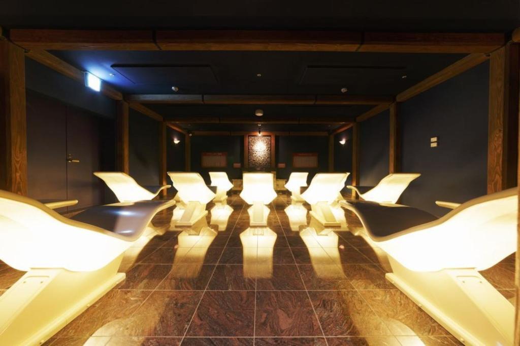a cinema room with white chairs and a spotlight at Spa World HOTEL&RESORT in Osaka
