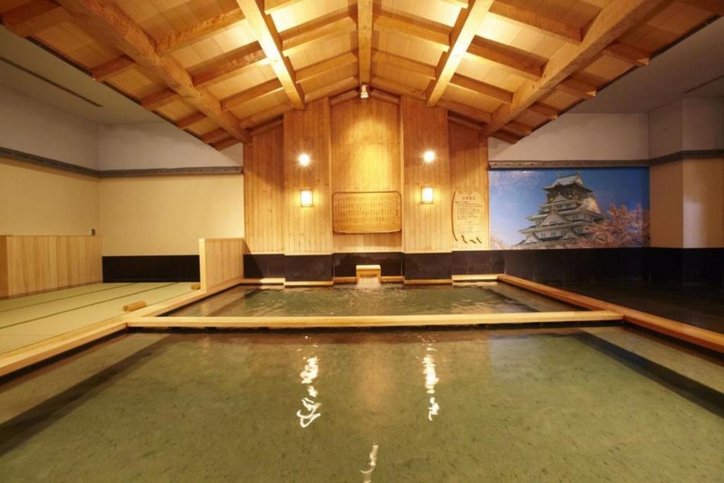an empty swimming pool in a room with wooden ceilings at Spa World HOTEL&RESORT in Osaka